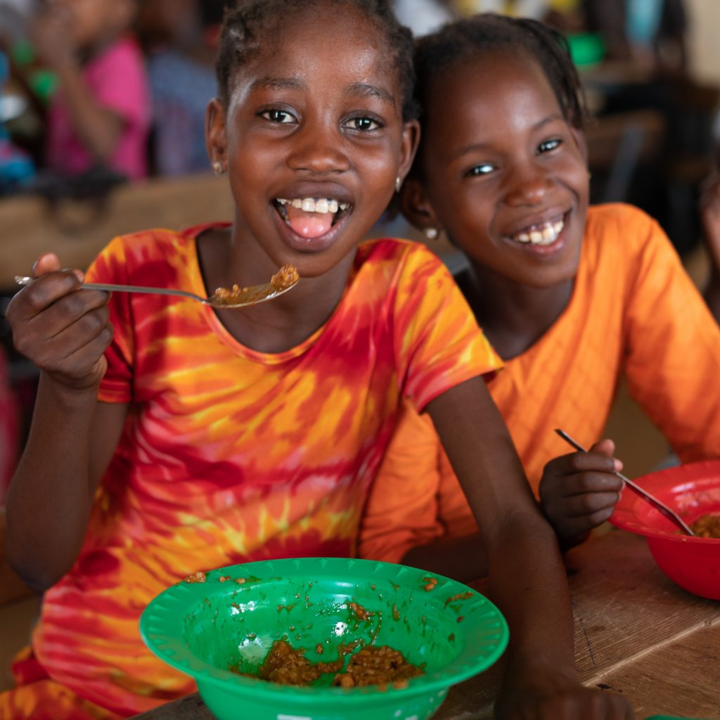 Zwei senegalesische Mädchen essen glücklich das Schulessen des World Food Programme.